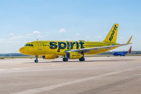 A yellow Spirt airline plane on the runway.